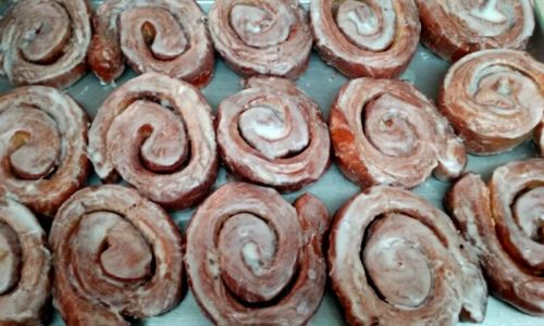 A tray of freshly baked cinnamon rolls with a glossy icing on top, arranged in a spiral pattern.