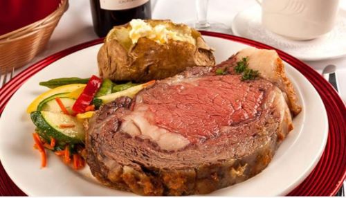 A plate featuring a juicy prime rib steak, baked potato, and colorful sautéed vegetables.