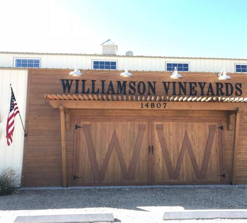 Exterior of Williamson Vineyards featuring a wooden facade, large doors, and an American flag.