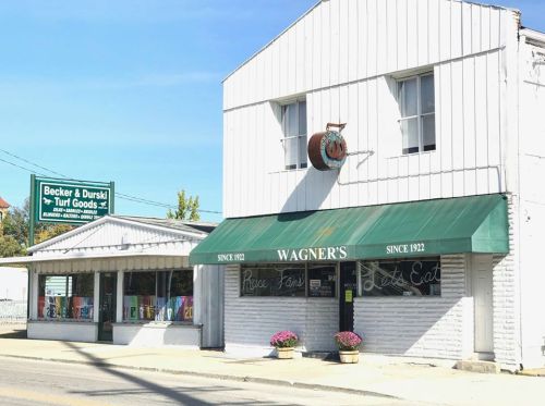 A white building with a green awning reading "Wagner's" and a sign for "Becker & Durski Turf Goods" nearby.