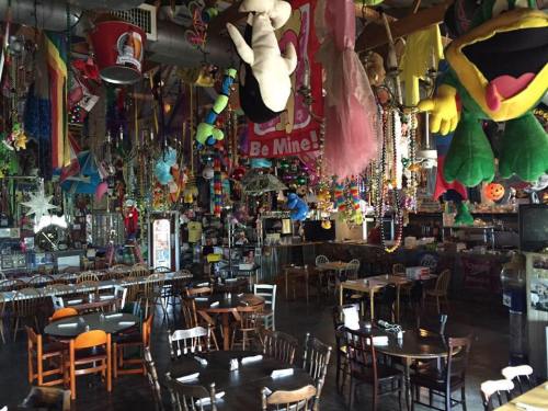A colorful, eclectic restaurant interior filled with hanging decorations, plush toys, and empty tables.