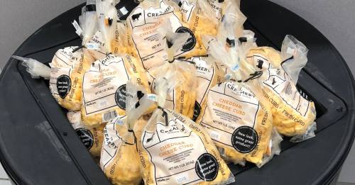 Bags of cheddar cheese curds displayed in a circular black container.