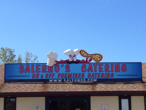 Sign for Salerno's Catering featuring a chef's hat and a peanut, with a blue background and clear sky above.