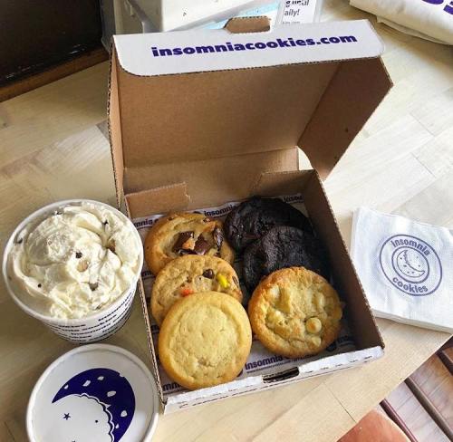 A box of assorted cookies from Insomnia Cookies, with a cup of ice cream and a napkin beside it.