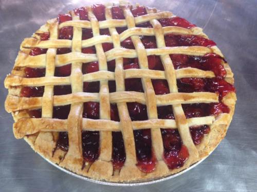 A freshly baked cherry pie with a golden lattice crust and glossy red filling.