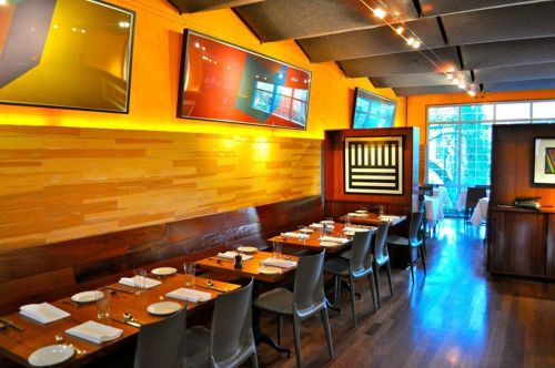 Modern restaurant interior with wooden tables, stylish chairs, and colorful artwork on the walls. Bright and inviting atmosphere.