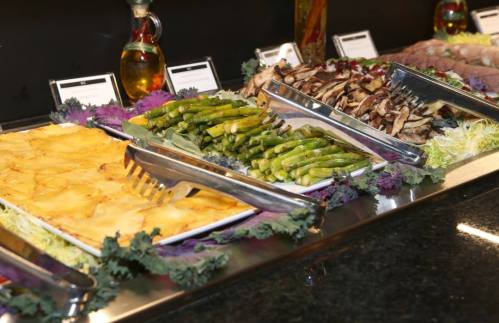 A buffet spread featuring baked potatoes, asparagus, and sautéed mushrooms on a decorative table.
