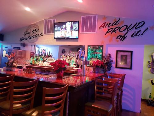 A cozy bar interior with a colorful display, featuring a TV, a well-stocked bar, and festive decorations.