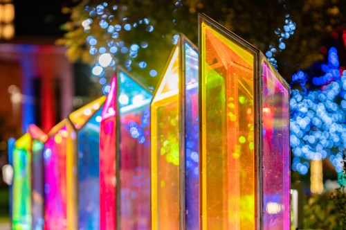 Colorful illuminated glass panels with vibrant reflections, set against a backdrop of twinkling lights.