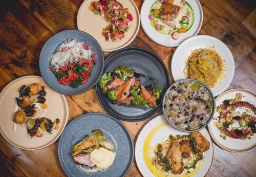 A variety of beautifully plated dishes, including pasta, meats, and vegetables, arranged on wooden table.