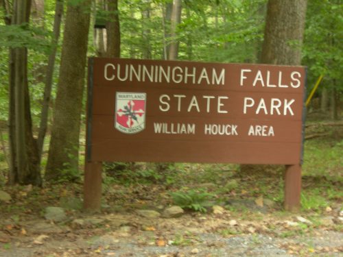 Sign for Cunningham Falls State Park, William Houck Area, surrounded by trees in a natural setting.