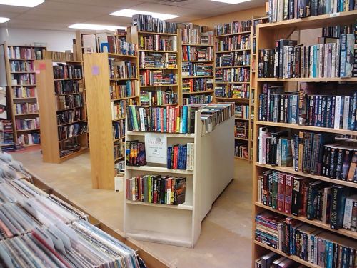 A cozy bookstore interior filled with tall shelves of books and a central display, inviting readers to explore.