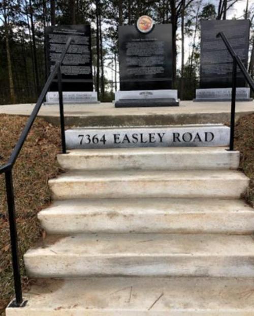 Steps leading to a memorial with black plaques, featuring the address "7364 Easley Road" at the base.