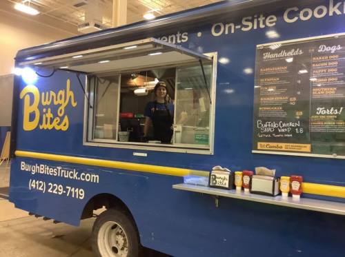 A food truck named "Burgh Bites" with a menu displayed, featuring a staff member at the service window.