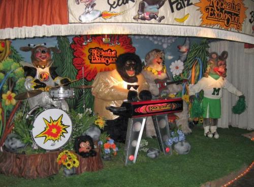 Animatronic band featuring a gorilla, bear, and mouse playing instruments in a colorful, whimsical setting.