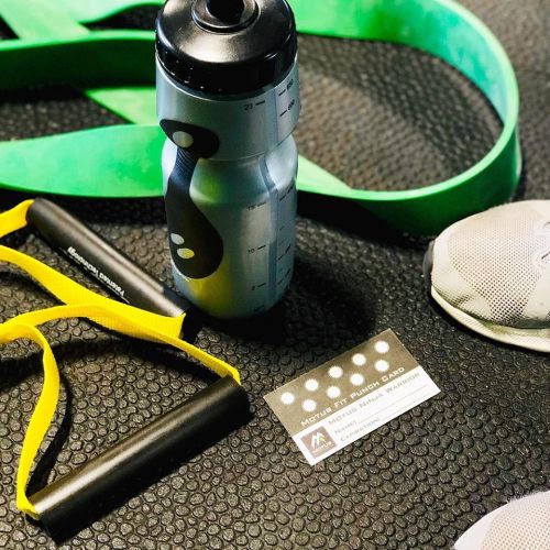 A water bottle, resistance bands, and a fitness card on a textured gym mat.