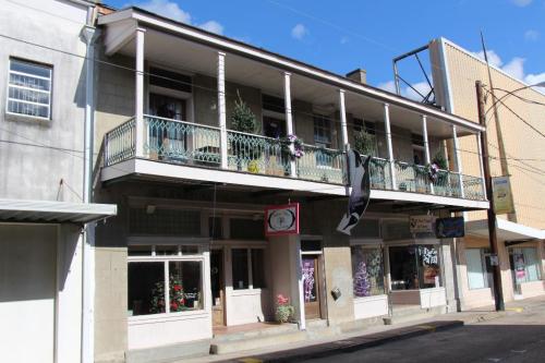 Historic building with a balcony, featuring storefronts below and decorative elements, set against a clear blue sky.