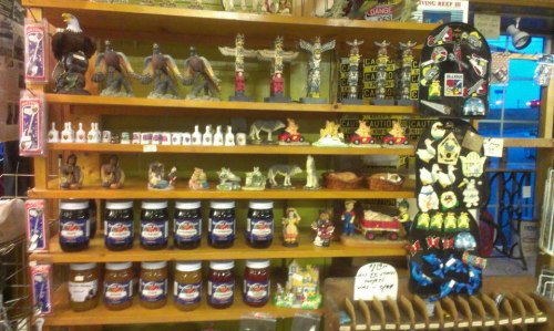 A wooden shelf displaying various decorative items, jars, and crafts, showcasing a colorful assortment of local goods.