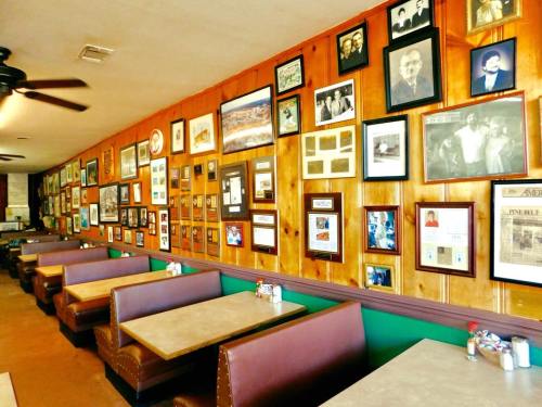 A cozy restaurant interior with wooden walls adorned with framed photos and memorabilia, featuring brown booths and tables.
