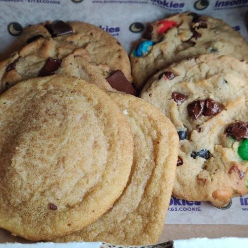 A box of assorted cookies, including chocolate chip and colorful candy cookies, arranged neatly.