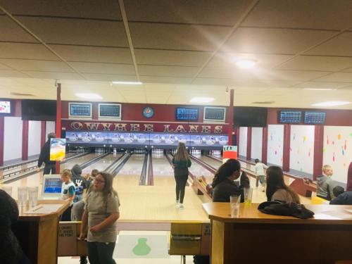 A bowling alley interior with lanes, screens, and people enjoying a game at Owyhee Lanes.