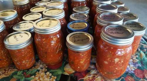 A collection of jars filled with homemade sauces, labeled with names like "The Pamper" and "Devil's Brew."