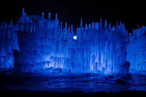 A stunning display of blue ice formations with sharp icicles illuminated against a dark background.