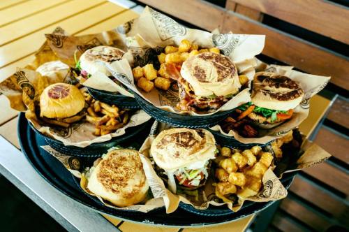 A tray filled with various burgers and tater tots, served in paper-lined baskets.