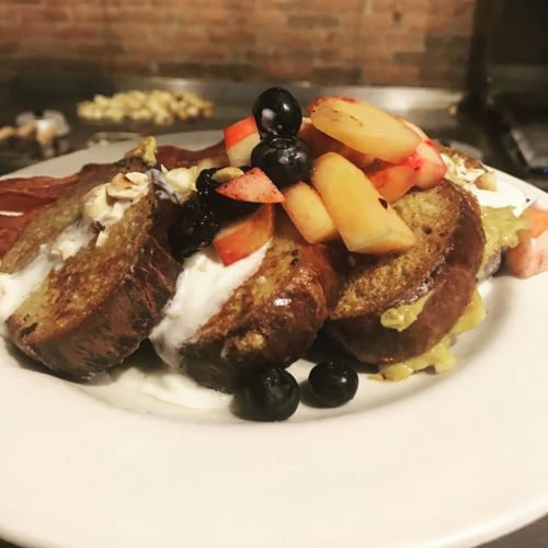 A plate of French toast topped with fresh fruit, blueberries, and a dollop of yogurt.