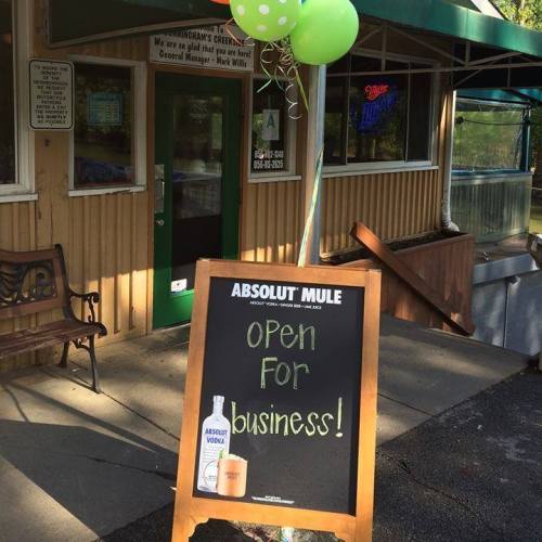 A sign outside a business reads "Open for Business!" with a drink advertisement and green balloons nearby.