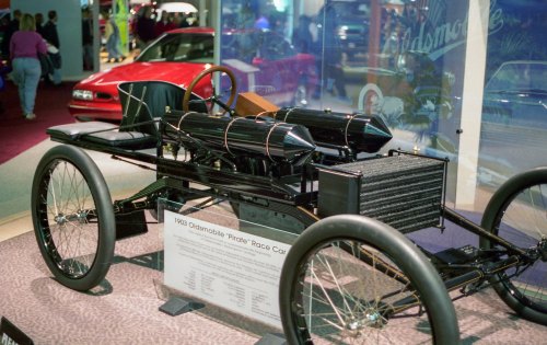 A vintage 1938 Oldsmobile "Pirate" race car displayed in a museum, showcasing its sleek, minimalist design.