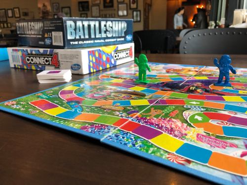 A colorful board game setup featuring Candy Land, with game pieces and boxes for Battleship and Connect 4 in the background.