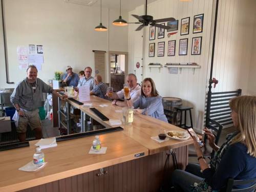 A group of people enjoying drinks at a bar, with a friendly atmosphere and various decorations on the walls.