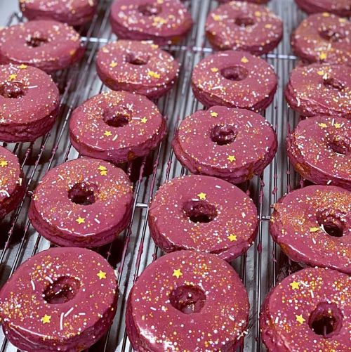 A tray of pink frosted donuts topped with colorful sprinkles and star-shaped decorations.