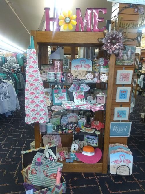 A display of home decor and gifts featuring flamingo designs, colorful signs, and summer-themed items.