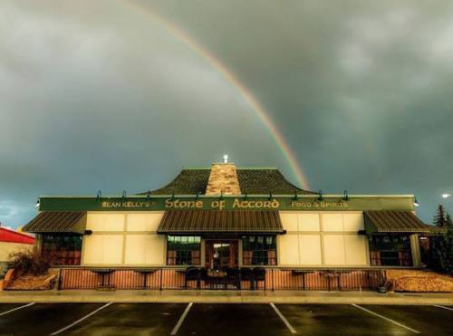 A restaurant building with a sign reading "Sean Kelly's Stone of Accord" under a rainbow and cloudy sky.