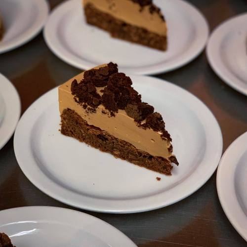 A slice of creamy dessert topped with chocolate crumbs, served on a white plate.