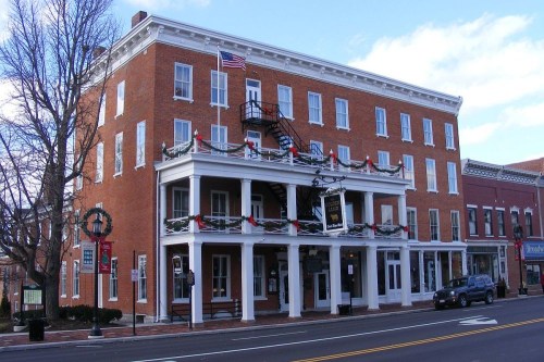 Historic brick building decorated for the holidays, featuring a flag, balcony, and festive garlands.