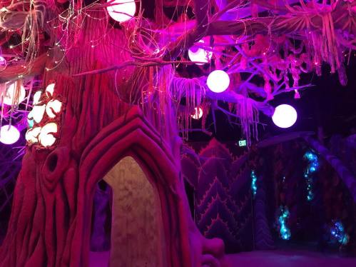 A vibrant, whimsical tree structure with glowing orbs and colorful, textured walls in a fantastical indoor space.