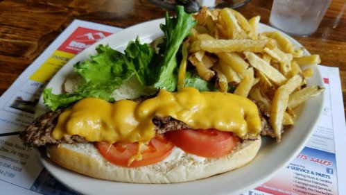 A plate featuring a cheesesteak sandwich with lettuce, tomato, and fries on the side.