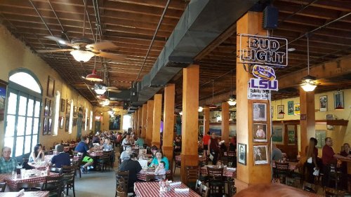 A bustling restaurant interior with wooden beams, tables filled with diners, and LSU memorabilia on the walls.