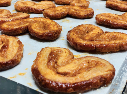 Golden-brown palmiers arranged on parchment paper, showcasing their flaky, caramelized texture.