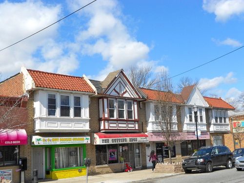 A row of colorful storefronts with distinct architectural styles under a blue sky with fluffy clouds.