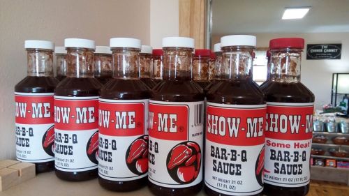 A row of bottles labeled "Show-Me Bar-B-Q Sauce" with a red and white design, showcasing different flavors.