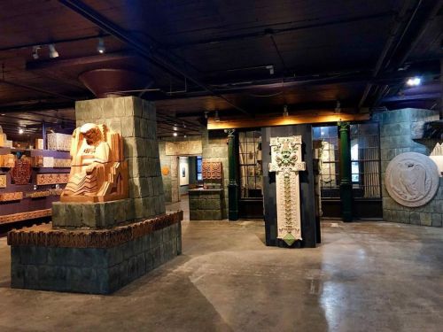 Artistic interior of a gallery featuring intricate stone sculptures and decorative wall panels in a well-lit space.