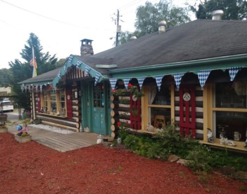 A charming log cabin-style building with colorful decorations and flower beds, featuring a welcoming entrance.