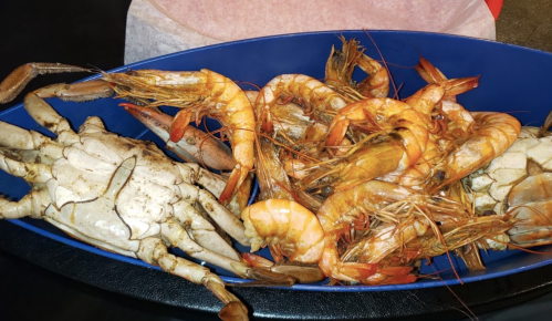 A blue bowl filled with various shrimp and a large crab.