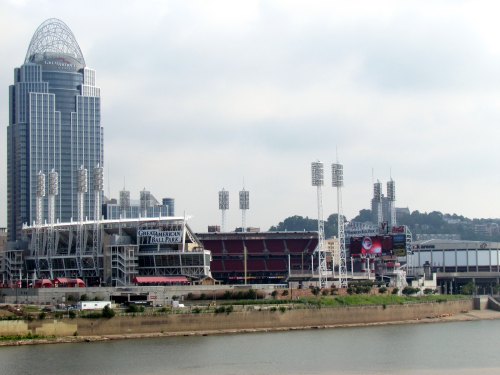 View of Great American Ball Park and skyline in Cincinnati, with the Ohio River in the foreground and cloudy skies.
