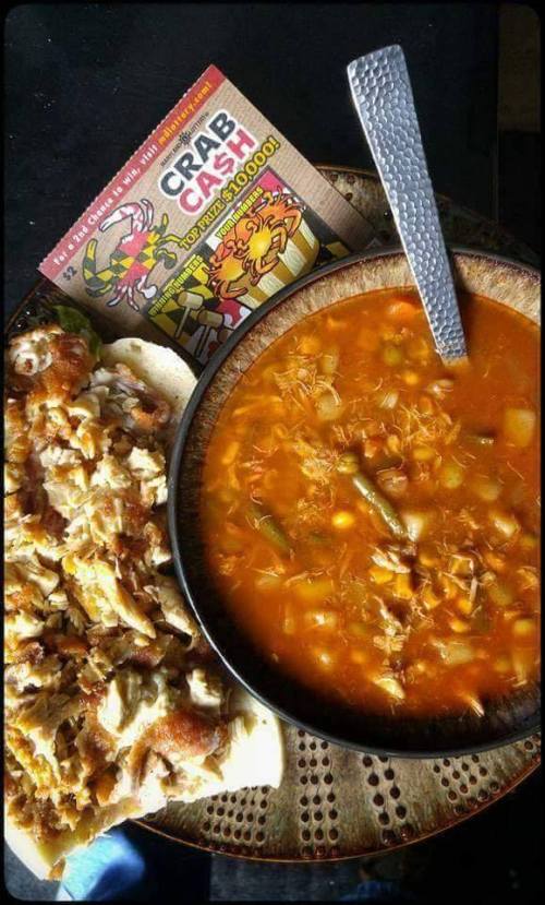 A bowl of soup with vegetables and shredded meat, alongside a plate of shredded meat on flatbread and a promotional card.