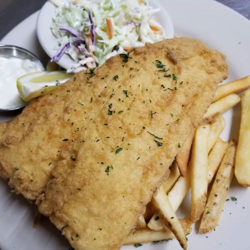 A plate of fried fish with fries, coleslaw, and a side of tartar sauce and lemon.